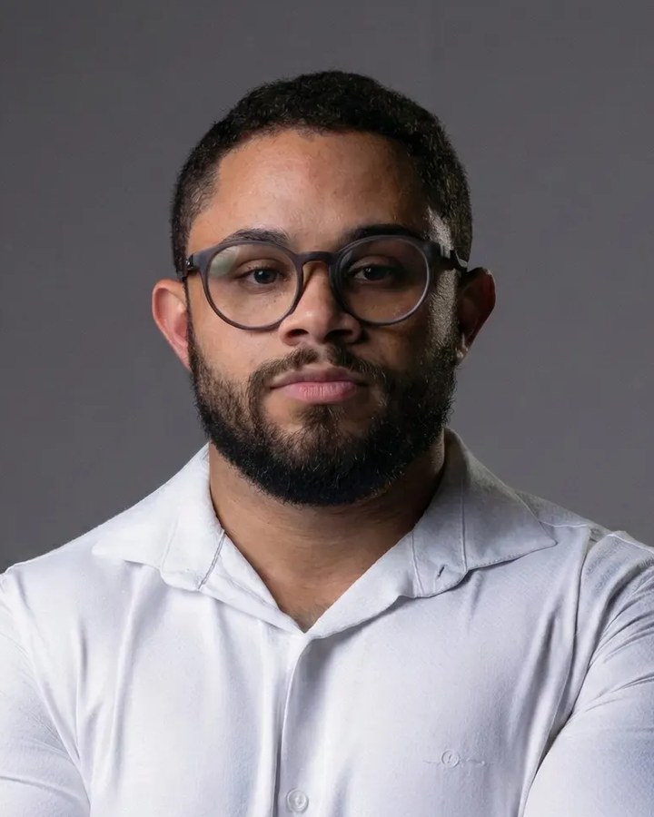 Lucas Norberto, nutricionista esportivo, de camisa branca e braços cruzados.